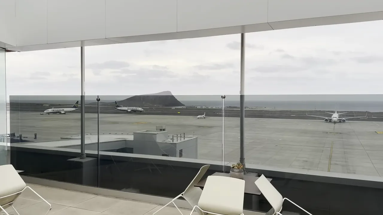 Outdoor terrace at Sala Montana Roja with white chairs, small cactus on a table and runway view